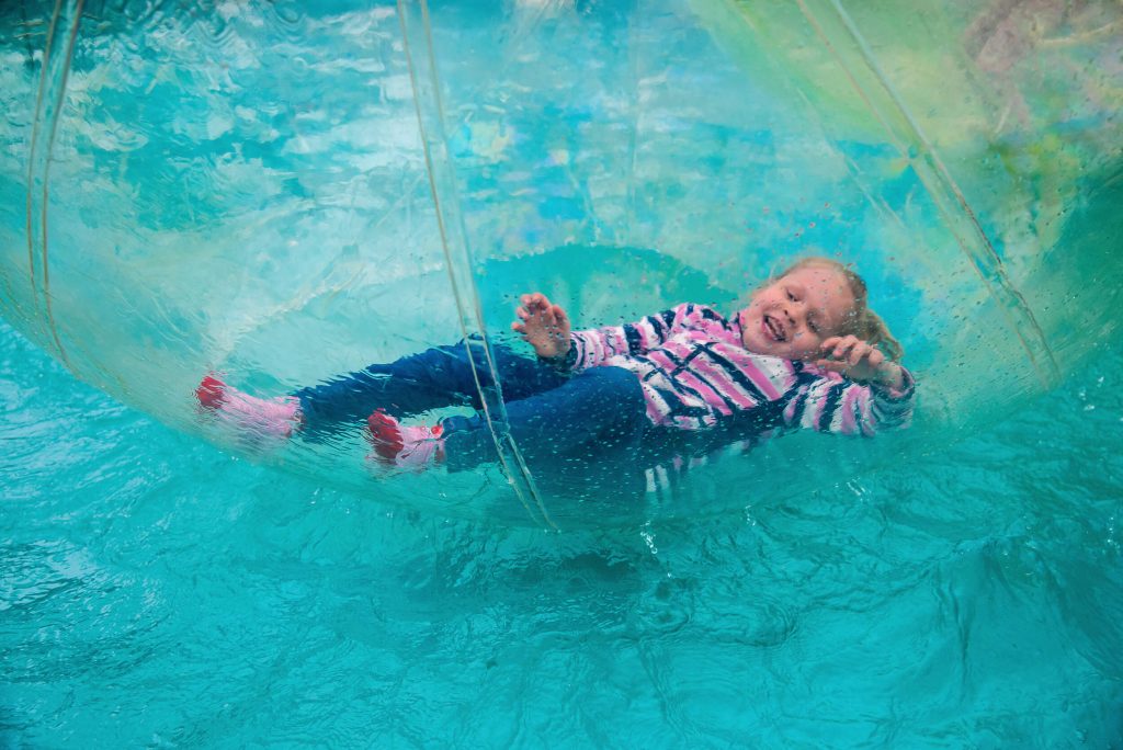 Young girl lying down in a water walkerz at Kielder Waterside